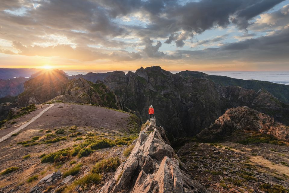 站立在岩石上面的妇女钦佩日落在Pico do arieiro，马德拉岛，葡萄牙