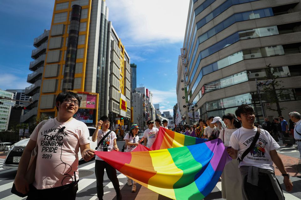 一群日本人举着一面巨大的彩虹自豪旗穿过城市的街道