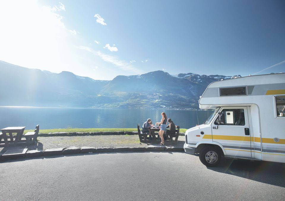 吃午餐的家庭在湖和山附近的Campervan