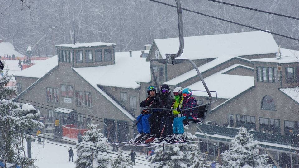 在滑雪缆车的一个家庭与度假村在背景中