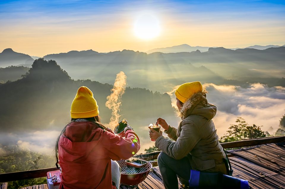 两个人在黄色豆享受一个热的饮料，当​​看在下面的山和雾