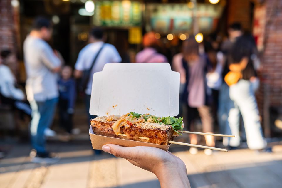 走拿着臭豆腐的少妇旅行者在台湾食物街道